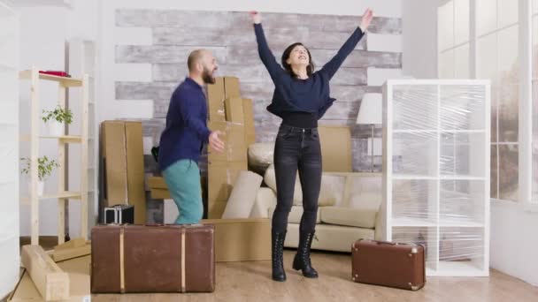 Glada unga par hoppar i sin nya lägenhet — Stockvideo