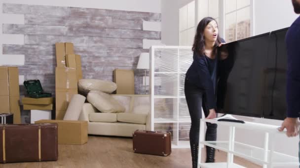 Pareja joven llevando una gran televisión en su nuevo apartamento — Vídeo de stock