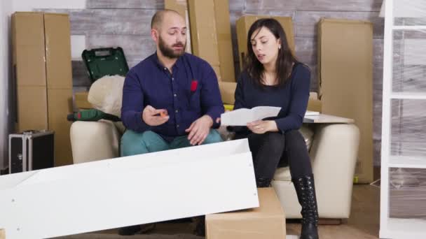 Jeune couple assemblant une étagère en équipe — Video