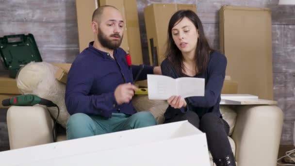 Barátnő és barát összeszerelése bútorok az új lakásban — Stock videók