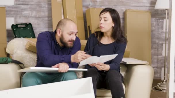 Pareja joven discutiendo mientras montan muebles en su nuevo apartamento — Vídeo de stock