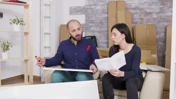 Couple montage de meubles en utilisant les instructions dans leur nouvel appartement — Video