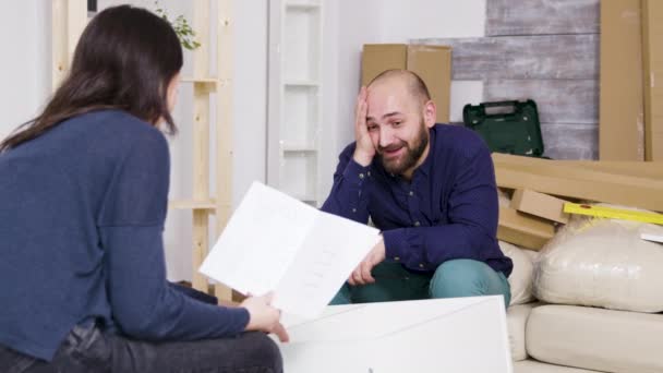 Confundida pareja joven mientras montan muebles en su apartamento — Vídeos de Stock