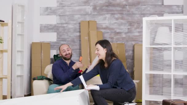 Young couple laughing while assembling furniture in their apartment — Stock Video