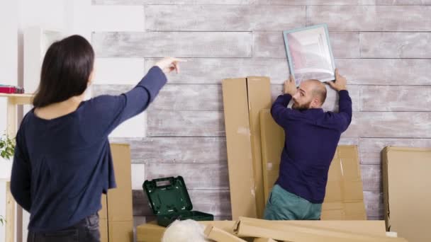 Happy young couple hanging picture on the wall — Stock Video