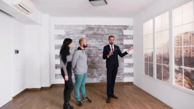 Başarılı bir emlakçı genç çiftle konuşuyor.