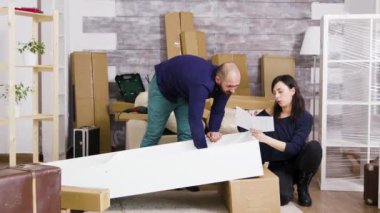 Yeni dairede takım olarak mobilya montajı yapan genç çift.
