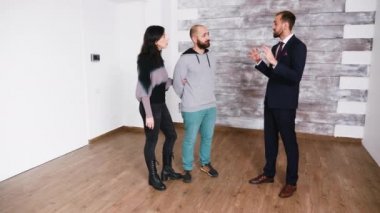 Sakallı emlakçı takım elbiseli, yeni bir daire gösteriyor.