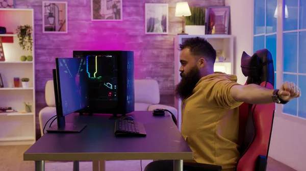 Baard man zitten op gaming stoel stretching tijdens het spelen van video games — Stockfoto