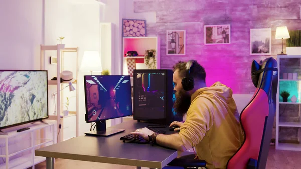 Hombre exitoso jugando videojuegos en línea en una habitación con coloridos neones — Foto de Stock