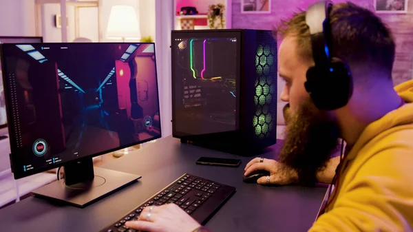 Hombre joven con auriculares mientras juega videojuegos en línea — Foto de Stock