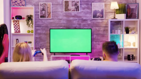 Young couple sitting on sofa and playing online games