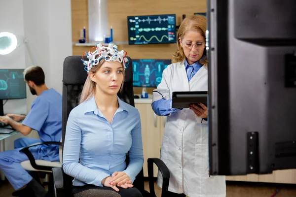 Mujer paciente con dispositivo de escaneo en la cabeza y médico programándolo con la tableta en la mano — Foto de Stock