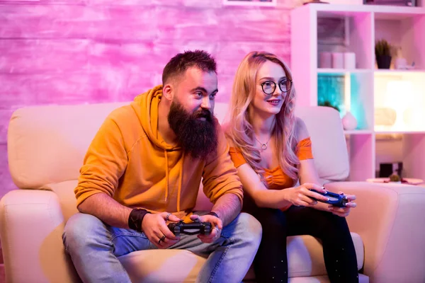 Giovane uomo e donna utilizzando controller wireless per giocare giochi online — Foto Stock