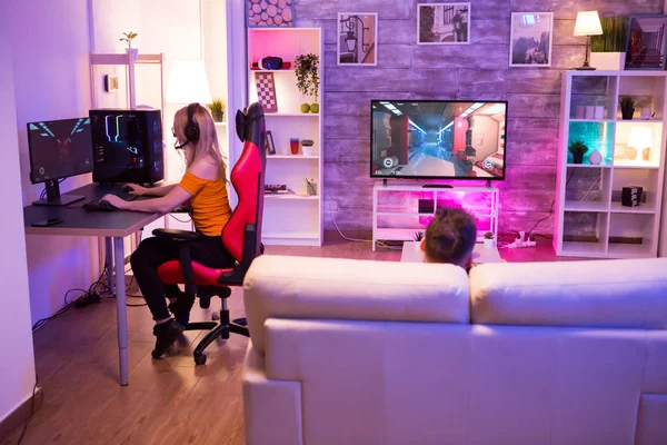 Menina loira jogando jogos de atiradores em uma sala com luz de néon — Fotografia de Stock