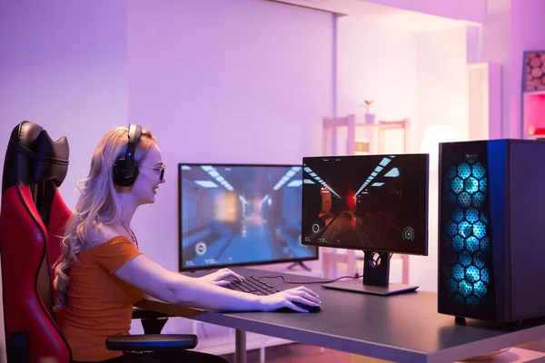 在电脑上玩网络游戏的金发女孩的侧视图 — 图库照片