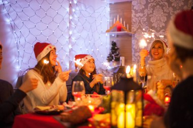 Güzel genç anne, Noel kutlamalarında ailesiyle birlikte havai fişeklere bakıyor.