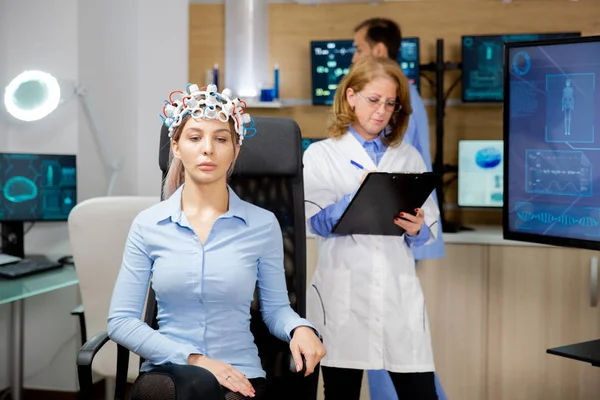 Médico que observa en el portapapeles la evolución del paciente durante la prueba de auriculares neurológicos —  Fotos de Stock