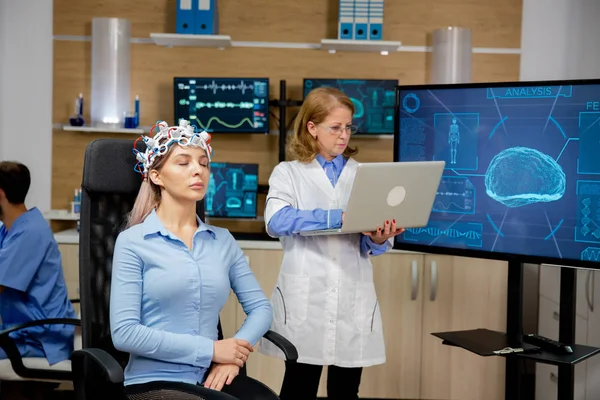 Médico analizando datos en vivo en una computadora portátil durante un procedimiento de escaneo cerebral de niñas —  Fotos de Stock