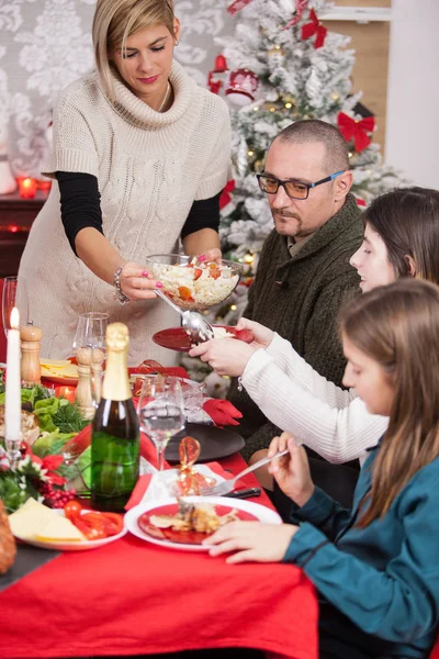 Gyönyörű fiatal kaukázusi anya adja át a salátát karácsonyi étkezés — Stock Fotó