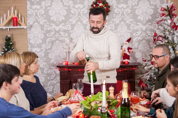 Yetişkin bir adam ailesiyle konuşur ve bir şişe şampanya açar. — Stok fotoğraf