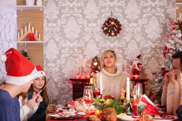 Belle jeune mère regardant la caméra tout en célébrant Noël avec la famille et les enfants jouant avec des feux d'artifice à la main — Photo