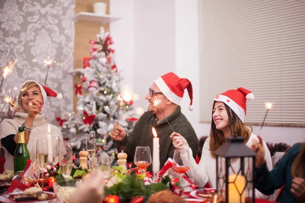 Vater und Tochter mit Weihnachtsmützen spielen bei Weihnachtsfeier mit Handfeuerwerk — Stockfoto