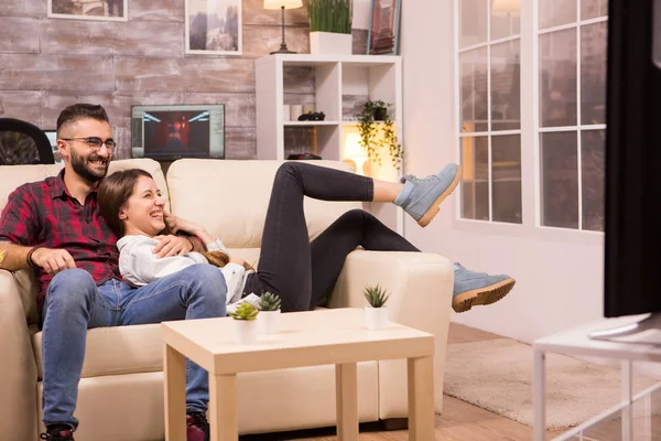 Bela jovem casal relaxante no sofá enquanto assiste a um filme na tv — Fotografia de Stock