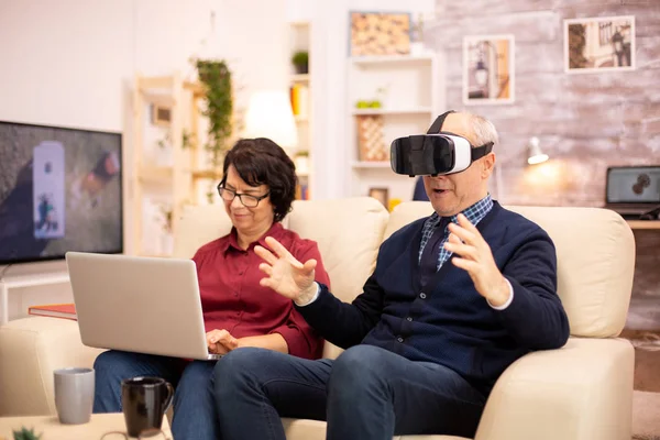 Idoso idoso aposentado homem usando realidade virtual headset em seu aconchegante apartamento — Fotografia de Stock