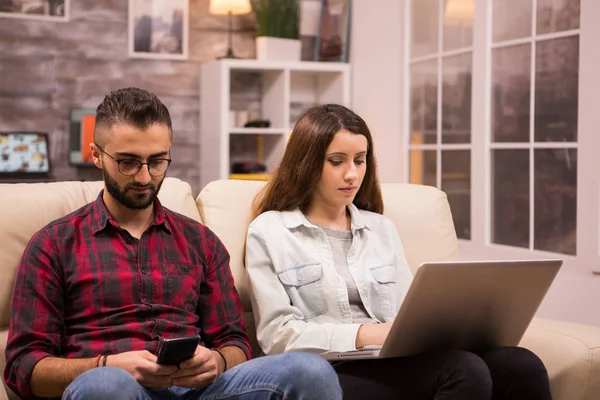 Молодая пара сидит на диване и делает покупки в Интернете — стоковое фото