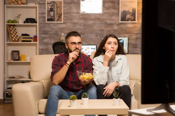 Mladý pár hledá soustředěný na televizi při sledování filmu — Stock fotografie