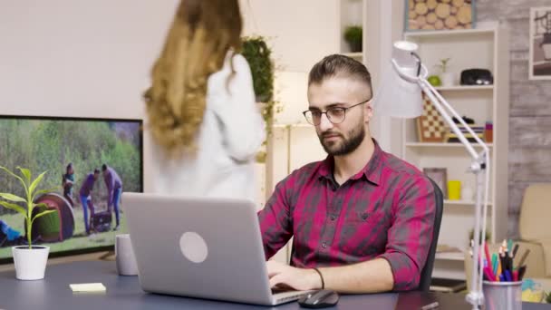 Jóképű férfi nevet, miközben a laptopon dolgozik a nappaliban — Stock videók