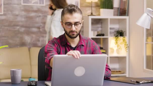 Empresario guapo tomando un sorbo de café mientras trabaja en el ordenador portátil — Vídeos de Stock