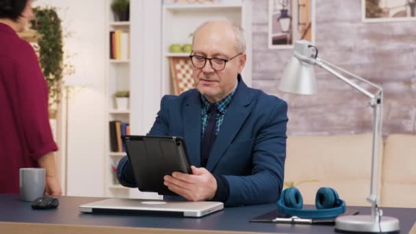 Elederly man met behulp van tablet tijdens het zitten op kantoor — Stockvideo