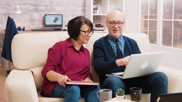 Ouderen leeftijd paar met behulp van laptop tijdens het zitten op de bank — Stockvideo