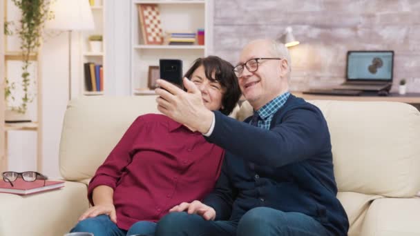 Heureux couple âgé assis sur canapé prendre un selfie — Video