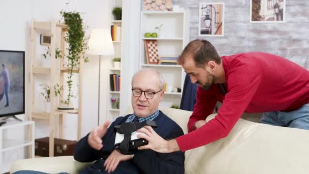 Hombre joven aprendiendo hombre viejo cómo usar auriculares VR — Vídeo de stock