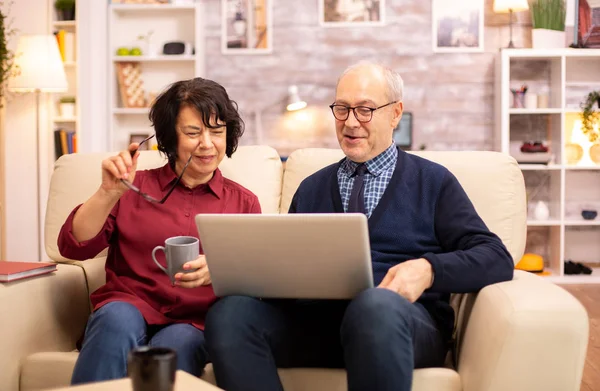 Elderly old couple using modern laptop to chat with their grandson