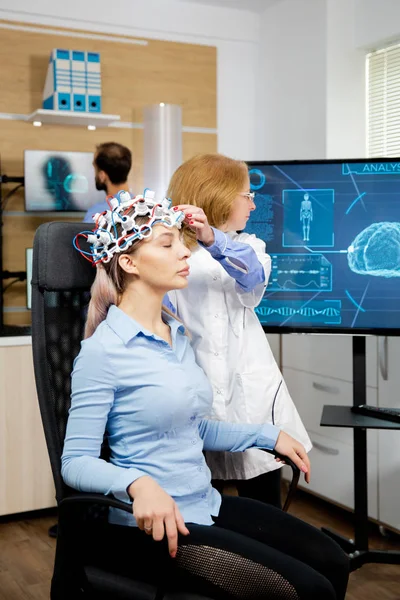 Médecin préparant le casque de balayage d'ondes cérébrales pour des tests — Photo