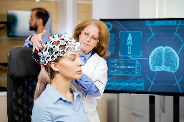 Врач организует неврологические сканирующие наушники для обследования пациентки — стоковое фото