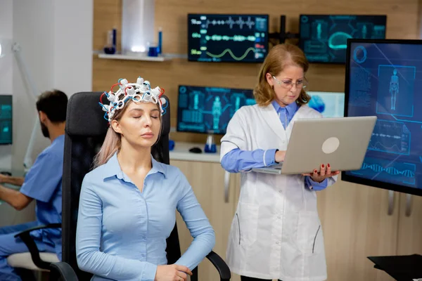 Doctor investigando datos en vivo en una computadora portátil durante un procedimiento de escaneo cerebral de niñas —  Fotos de Stock