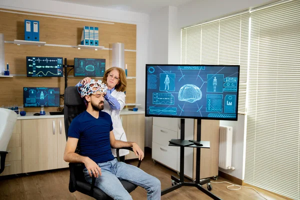 Doctor instalando dispositivo de escaneo en la cabeza de un paciente masculino . —  Fotos de Stock