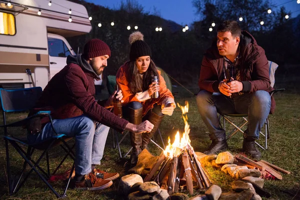 Los campistas se relajan juntos alrededor del fuego del campamento — Foto de Stock