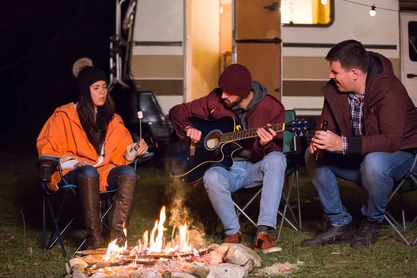 Jóvenes amigos asando malvaviscos sobre fuego de campamento — Foto de Stock