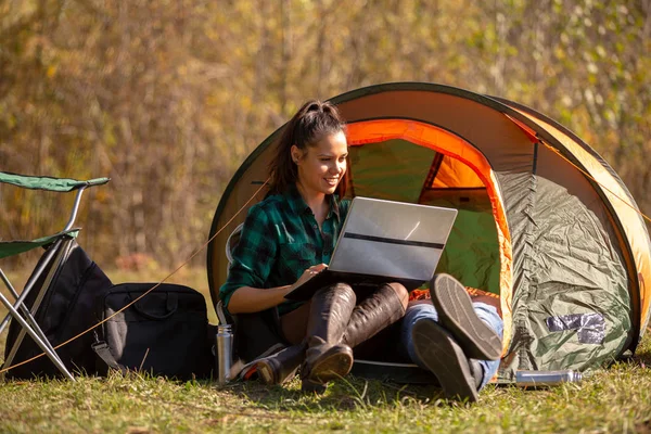 Młoda dziewczyna pracuje na laptopie przyjaciół obok namiotu — Zdjęcie stockowe