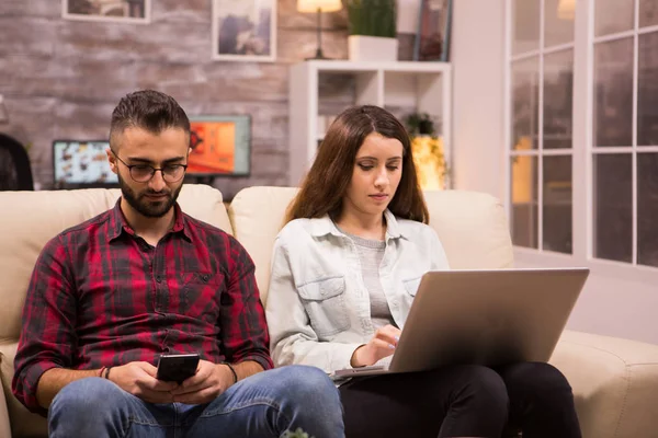 Молодая пара сидит на диване и делает покупки в Интернете — стоковое фото