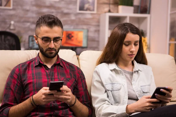 Jovem casal obcecado com smartphones verificando redes sociais — Fotografia de Stock