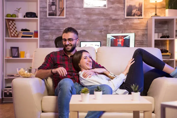 Alegre jovem casal rindo enquanto assiste a um programa de TV — Fotografia de Stock