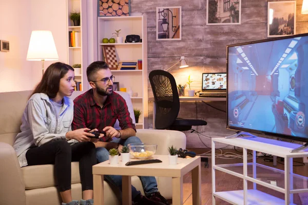 Парень учит свою девушку играть в видеоигры на телевидении — стоковое фото