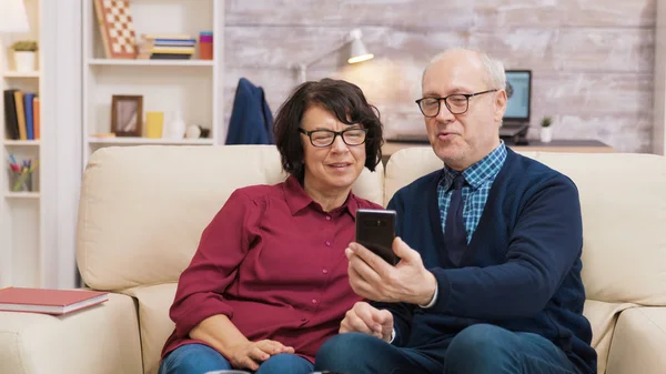 老人和女人用他们的智能手机打一个视频电话 — 图库照片